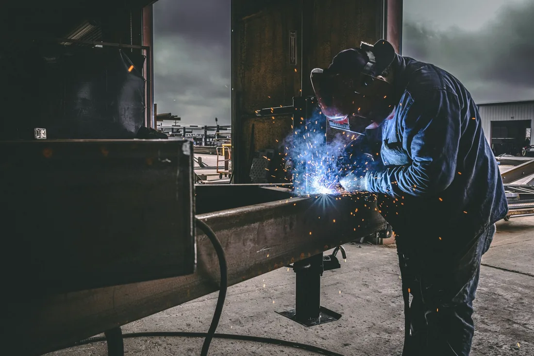Welder joining steel components in a fabrication workshop